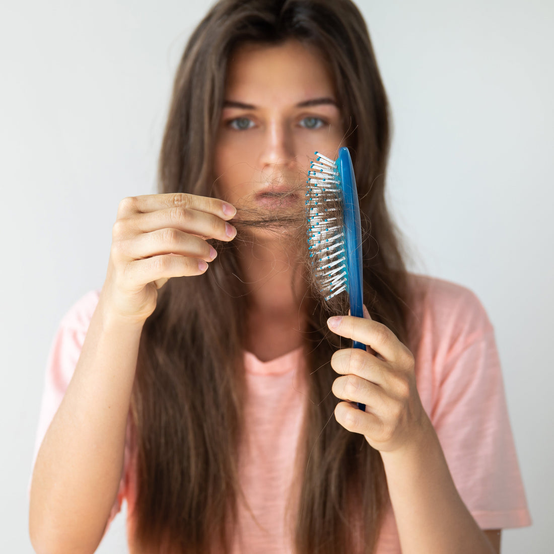 Woman examining hair part in mirror, representing early signs of hair thinning and natural hair loss solutions
